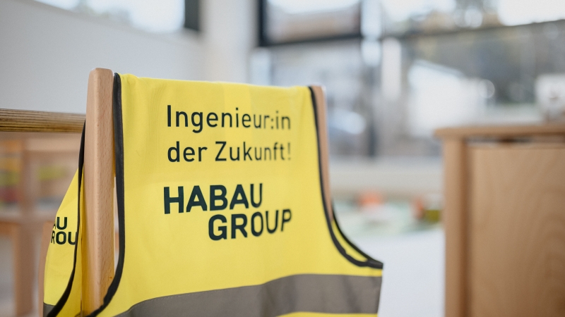 Warnweste von der HABAU GROUP hängt auf einem Stuhl